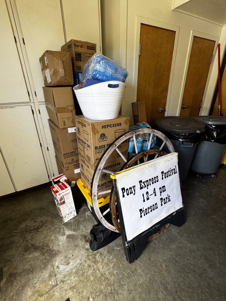 Pony Express Days festival sign, boxes, supplies, and trash cans staged before the event in McKinleyville.
