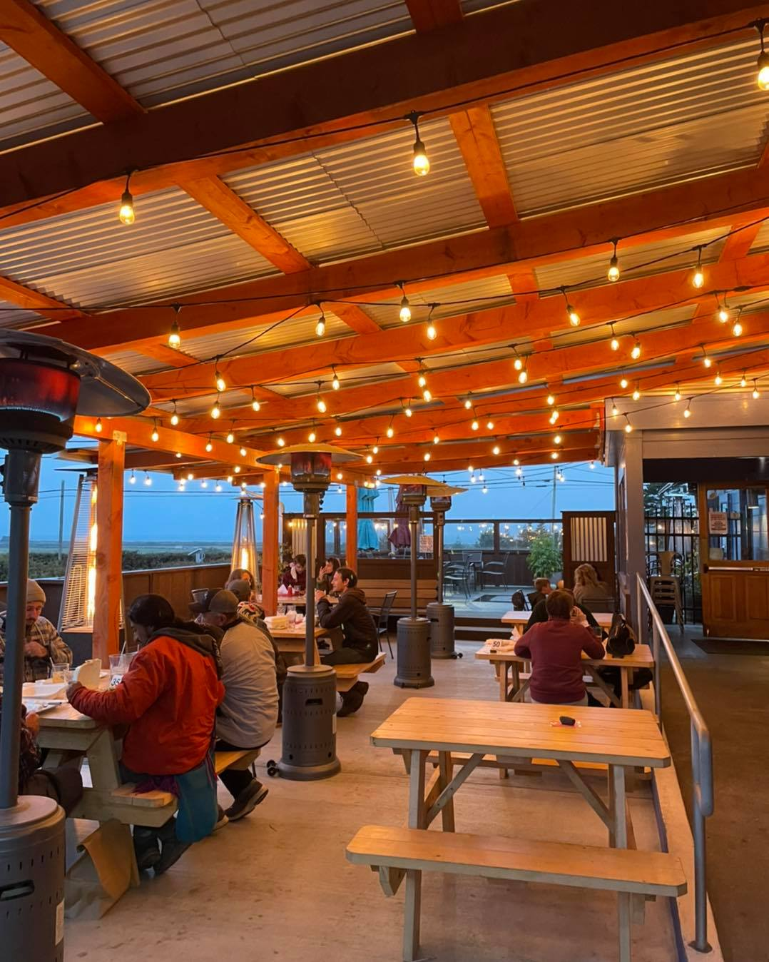 People gathering on a local outdoor dining patio beneath warm string lights