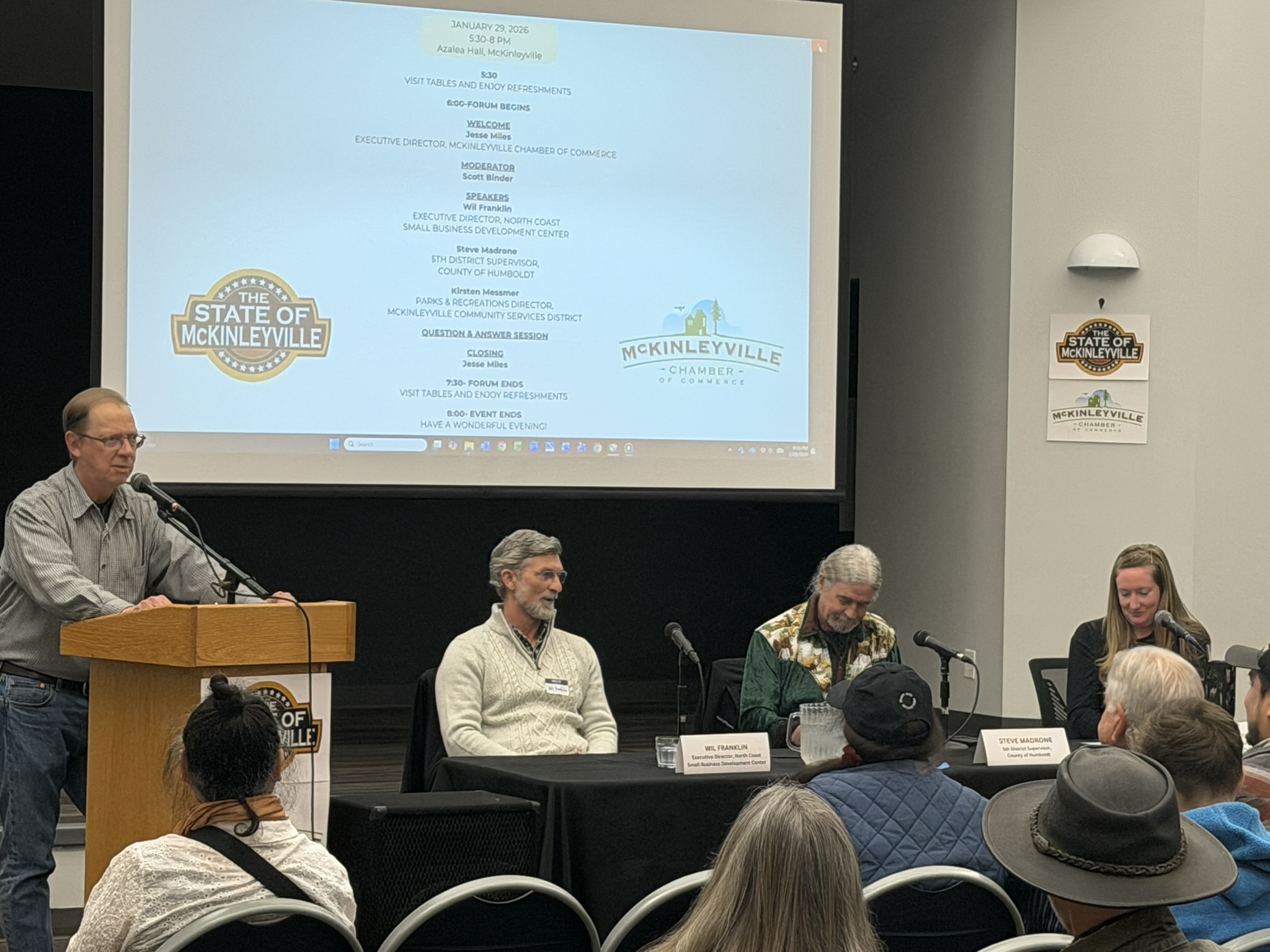 Moderator at the podium beside three seated panelists at the 2026 State of McKinleyville forum.