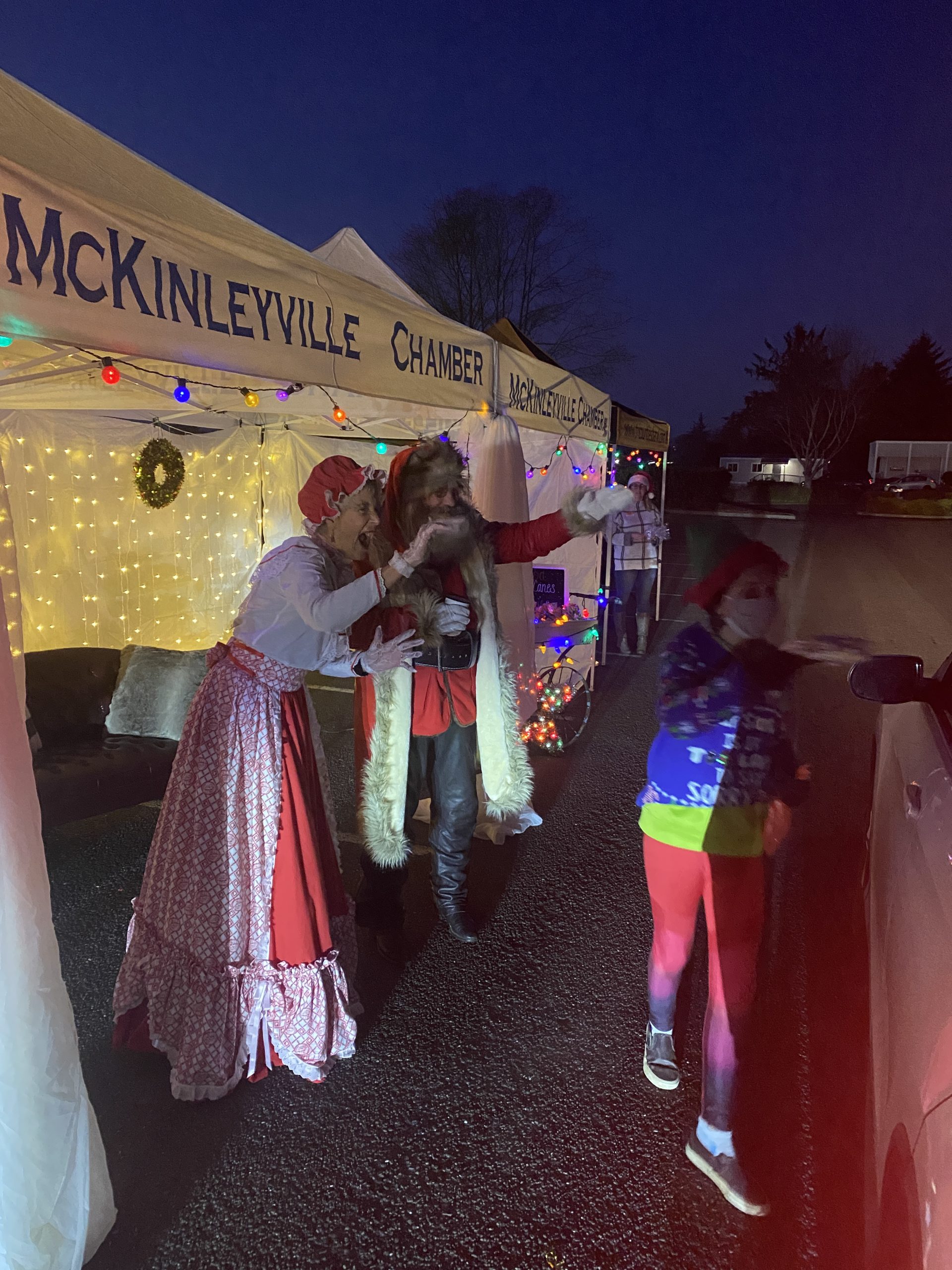 Santa and Mrs. Claus greeting a child at the decorated McKinleyville Chamber tent